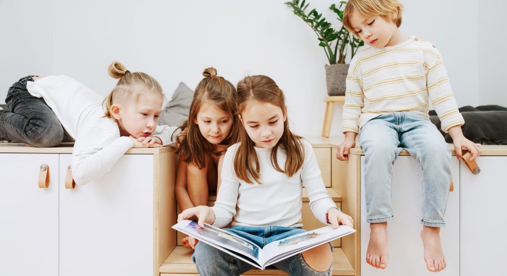 Vier Kinder sitzen zusammen und schauen in ein Buch