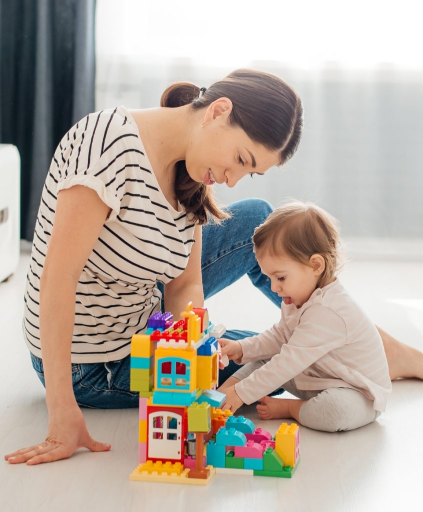 Frau mit Kind am Spielzeughaus bauen