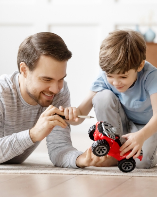 Mann repariert mit jungem Bub ein Spielzeugauto